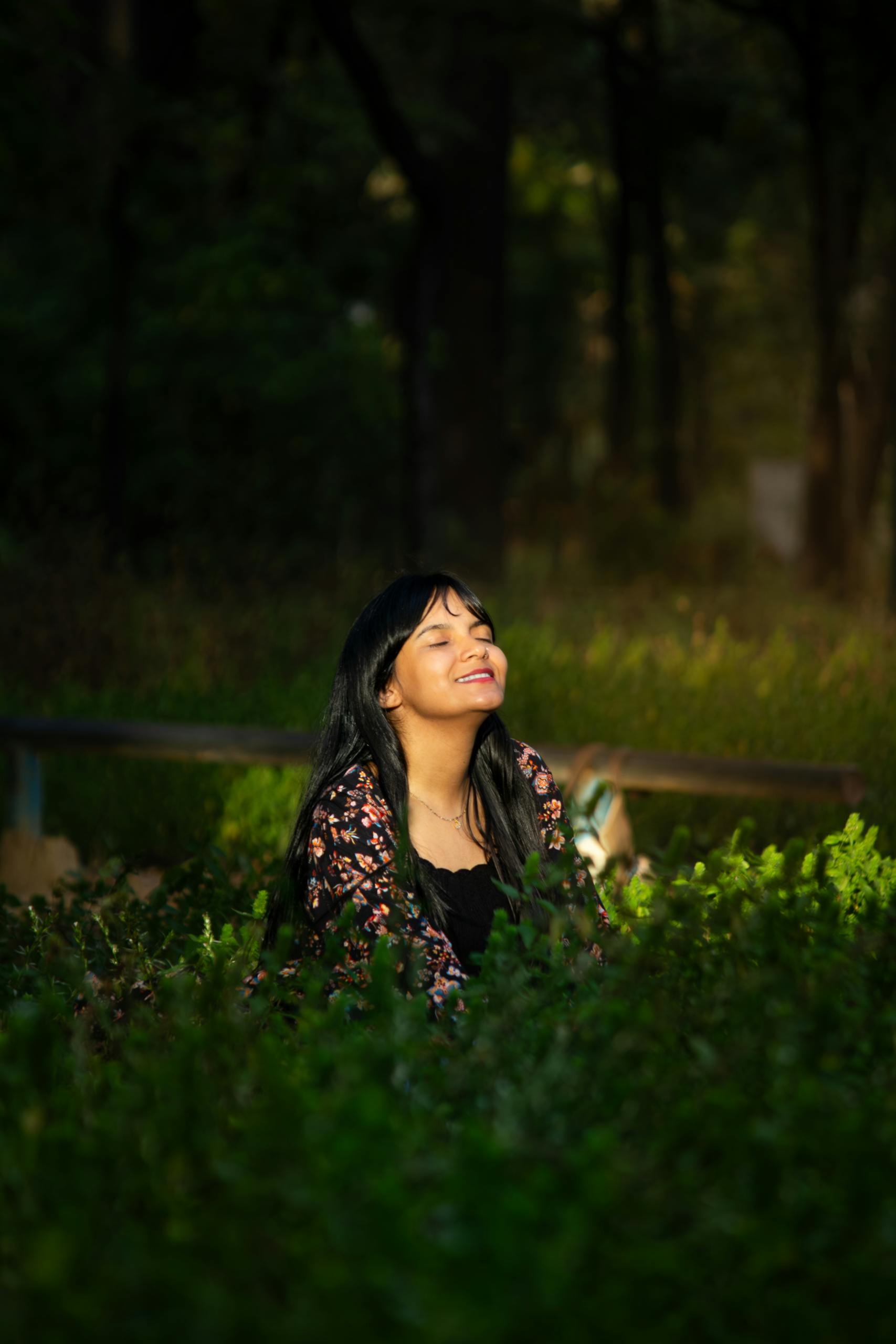 A woman basks in the sunlight surrounded by lush greenery in a forest setting.